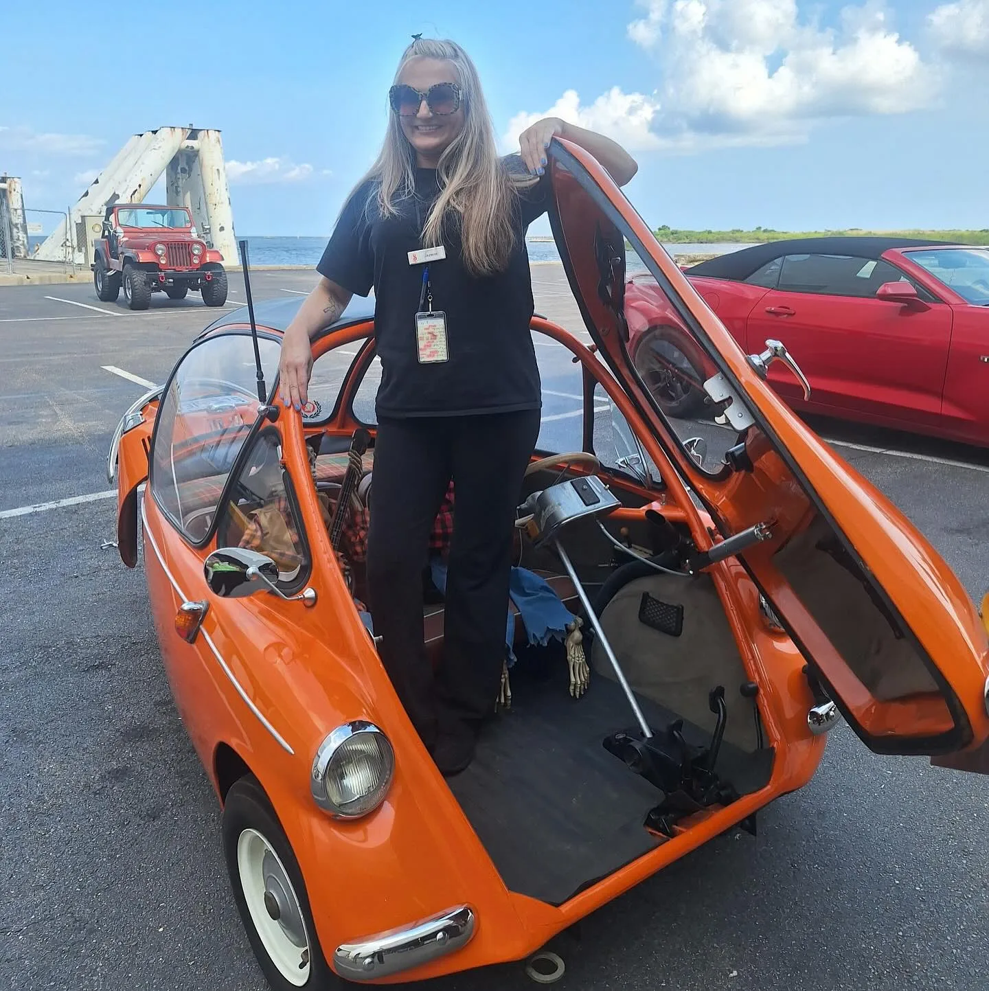 Guest beside an orange bubble-top microcar with its canopy open