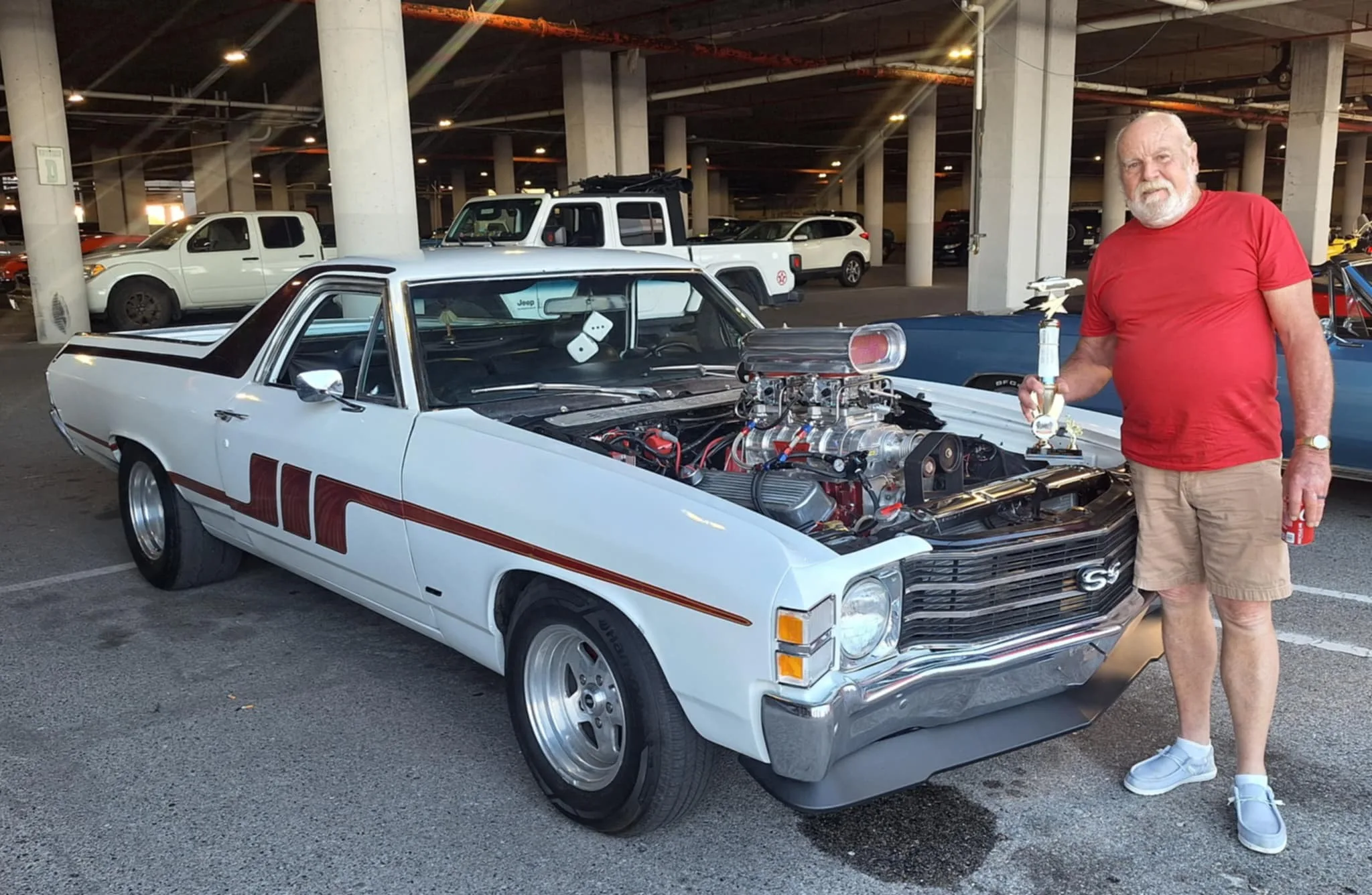 Owner beside a white classic El Camino with a chrome blower
